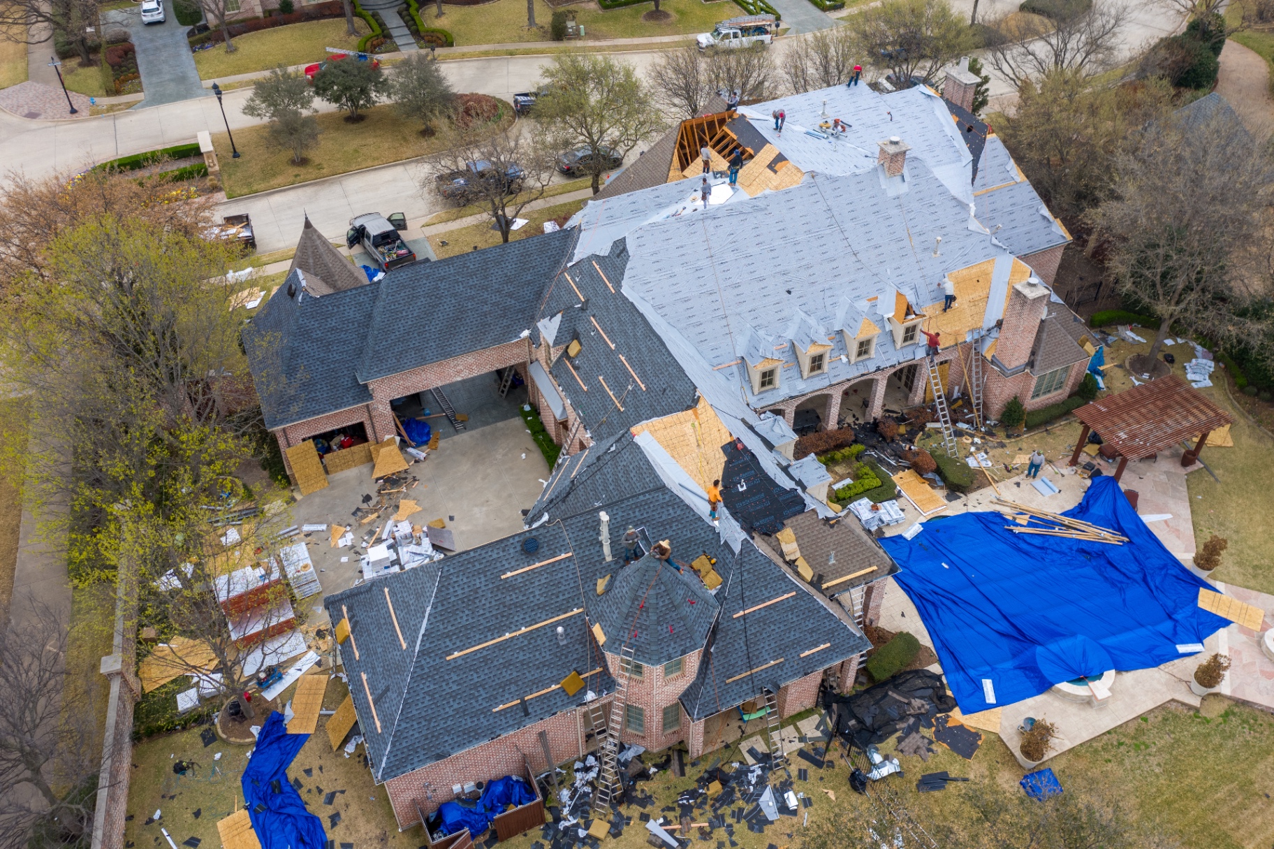Aerial view of a Stonebriar roofing crew replacing a large DFW home's roof